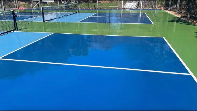 Multi-colour all-weather tennis court surfaces in blue and green with white boundary lines and net posts.
