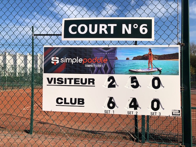 A tennis scoreboard at Court N°6 showing the Visiteur leading 2–5 in the top line and Club 6–4 in the bottom line, with a