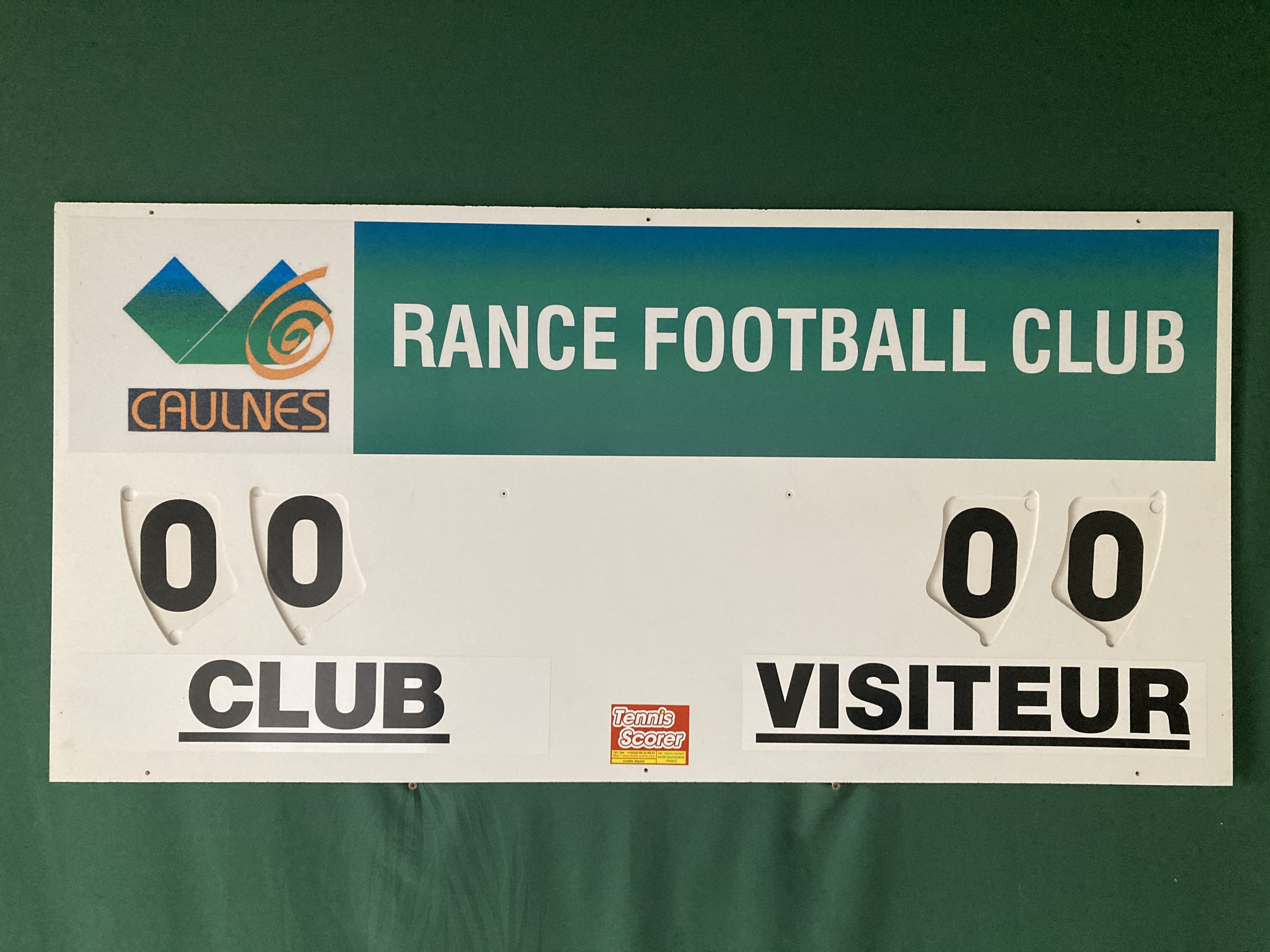 Großes Spielstandsschild mit zwei runden Ziffern-Tafeln zeigt CLUB gegen VISITEUR auf dem Spielfeld.