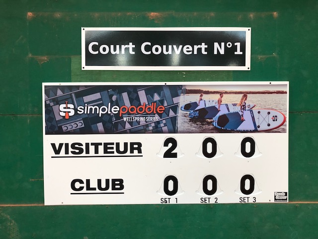 Panneau d’affichage d’un terrain de sport montrant le score Visiteur 2, Club 0, avec trois sets en cours.