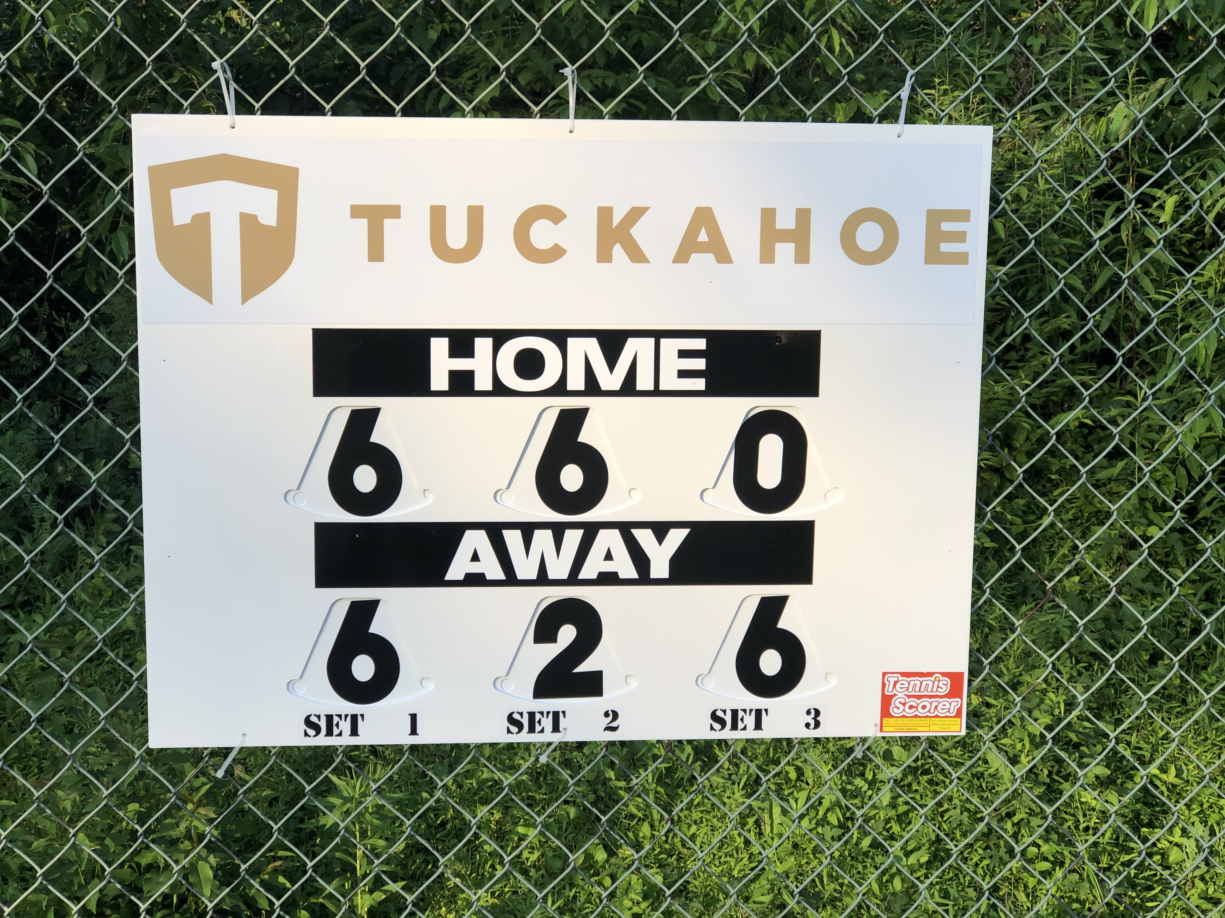 Tuckahoe home score board on a chain‑link fence showing 6‑6‑0 for home and 6‑2‑6 for away.